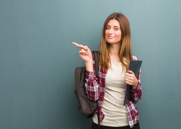 Giovane studente che sorride e che indica il lato