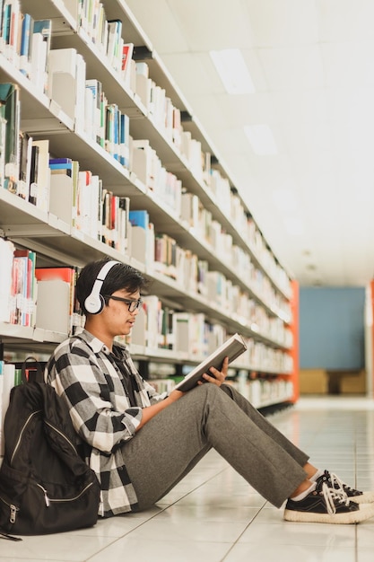 Giovane studente che studia ricerca e ascolta musica in cuffia