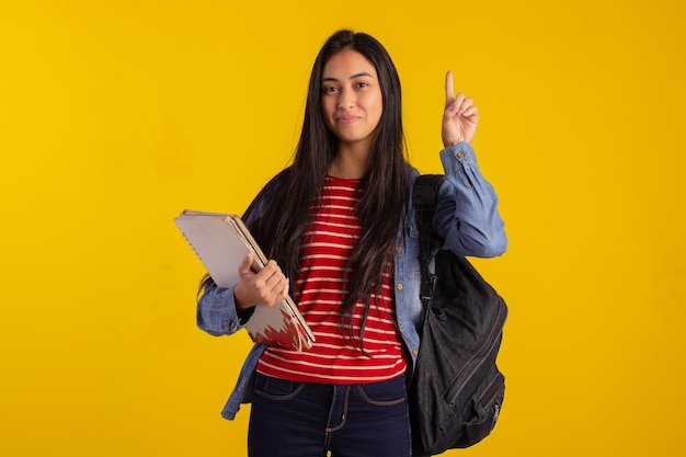 Giovane studente che tiene zaino e libri in studio fotografico