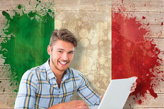 Giovane studente che utilizza il computer portatile contro la bandiera dell'italia in effetto grunge