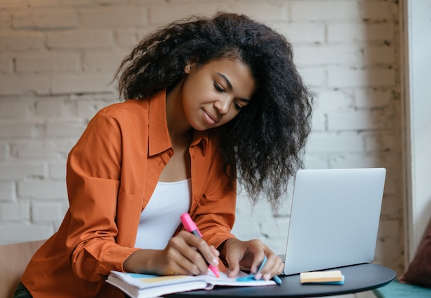 Giovane studente con laptop, prendere appunti, studiare a casa, apprendimento a distanza