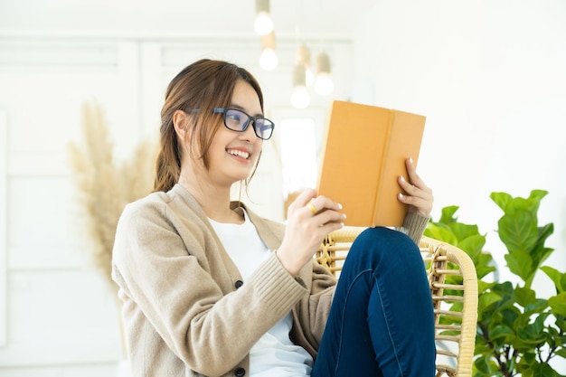 Giovane studente di collage che legge un libro seduto su una sediaxA