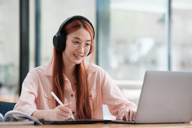 Giovane studente di collage che usa computer e dispositivi mobili per studiare online