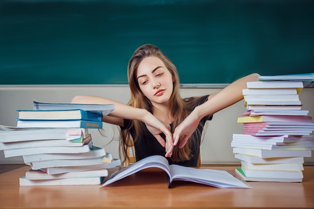 Giovane studente di college alla preparazione dura dell'esame nella sala dello studio che sembra stanco e stanco