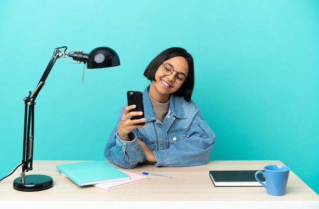 Giovane studente di razza mista donna che studia su un tavolo facendo un selfie