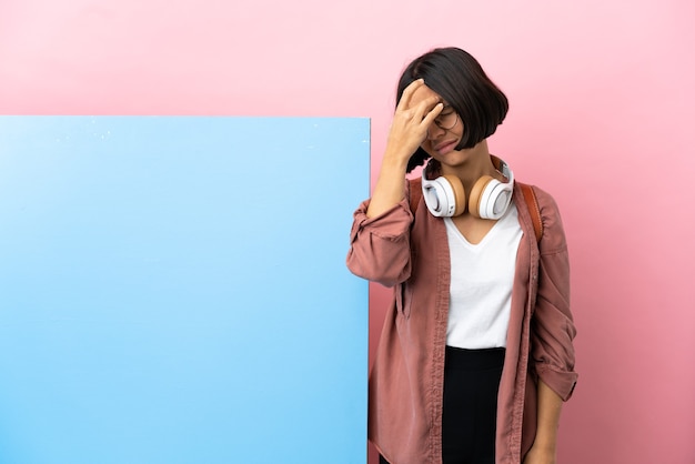 Giovane studente di razza mista donna con un grande striscione sul muro isolato con mal di testa