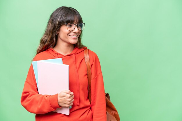 Giovane studente donna caucasica su sfondo isolato guardando al lato e sorridente