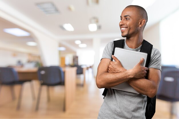 Giovane studente in camicia grigia che tiene il taccuino e sorride