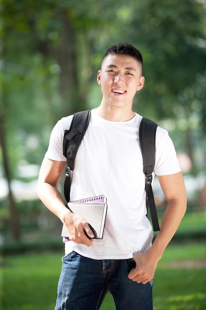 Giovane studente maschio bello asiatico all'aperto nel parco