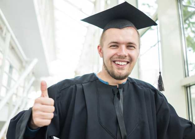 Giovane studente maschio in abito nero laurea