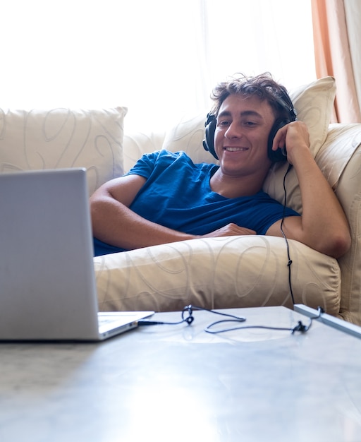 Giovane studente sul divano che guarda film con il computer portatile giovani con uno stile di vita moderno