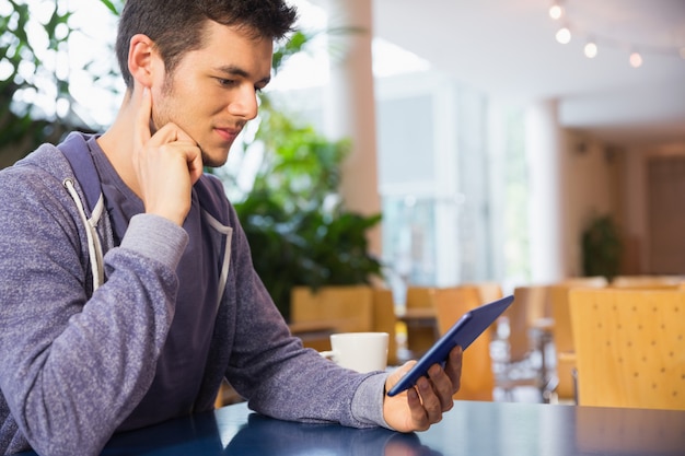 Giovane studente usando il suo tablet nella caffetteria