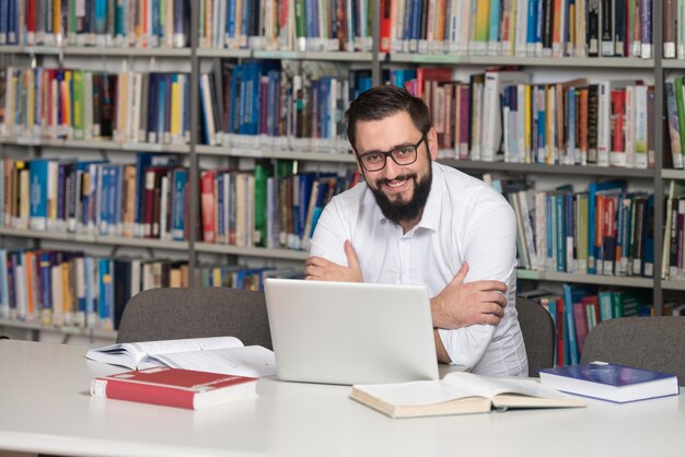 Giovane Studente Utilizzando Il Suo Computer Portatile In Una Biblioteca