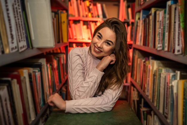 Giovane studentessa alla ricerca di un libro nella biblioteca universitaria