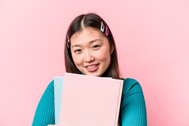 Giovane studentessa asiatica che tiene libri isolati su sfondo rosa