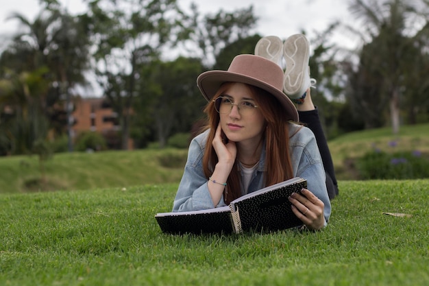 giovane studentessa bellissima che legge un libro in un parco in una biblioteca universitaria