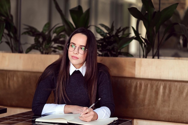 Giovane studentessa carina che studia al caffè verde