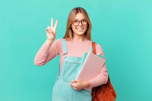 Giovane studentessa che sorride e sembra amichevole, mostrando il numero due