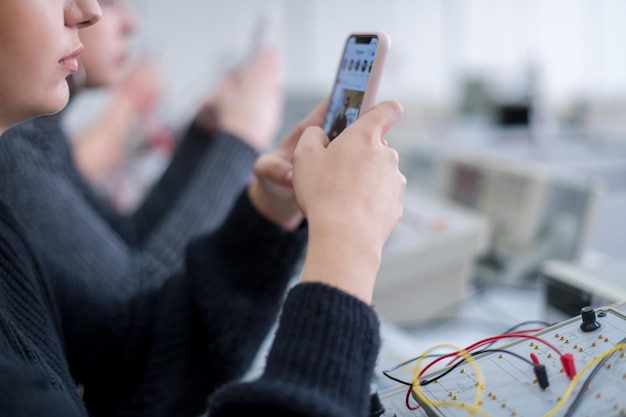 giovane studentessa che utilizza un telefono cellulare durante la pausa nell'aula di elettronica