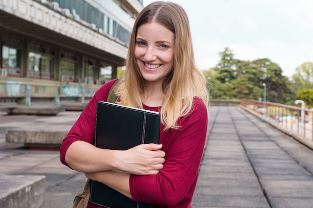 Giovane studentessa con le cartelle nel campus universitario