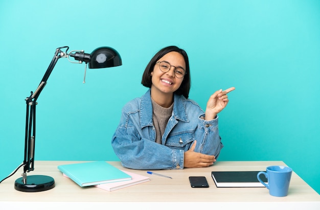 Giovane studentessa di razza mista che studia su un tavolo puntando il dito di lato