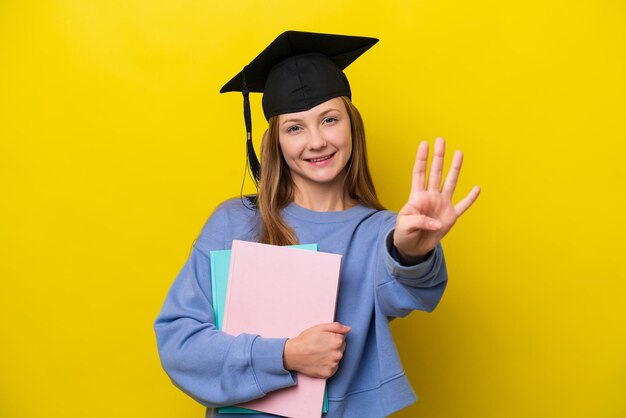 Giovane studentessa russa isolata su sfondo giallo felice e contando quattro con le dita