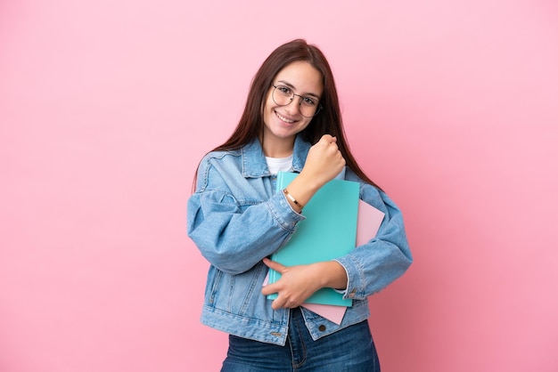 Giovane studentessa ucraina isolata su sfondo rosa che celebra una vittoria