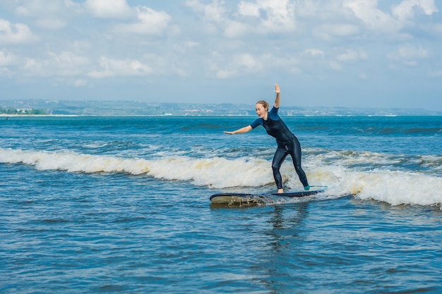 Giovane surfista principiante gioioso con surf blu si diverte sulle piccole onde del mare Stile di vita familiare attivo persone lezione di sport acquatici all'aperto e attività di nuoto durante le vacanze estive del campo di surf