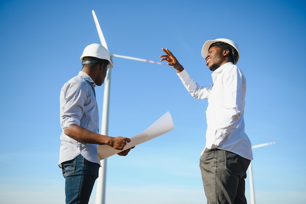 Giovane team di ingegneri di manutenzione che lavora in una fattoria di turbine eoliche al tramonto stock photo