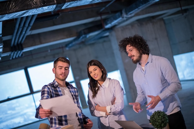 giovane team di uomini d'affari in gruppo, architetto e ingegnere in cantiere che controllano i documenti e il flusso di lavoro aziendale utilizzando un computer portatile nel nuovo ufficio di avvio