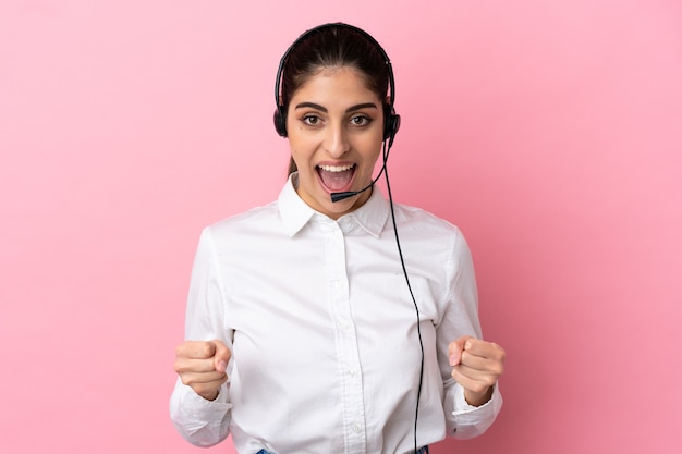 Giovane telemarketer su sfondo isolato che celebra una vittoria nella posizione del vincitore