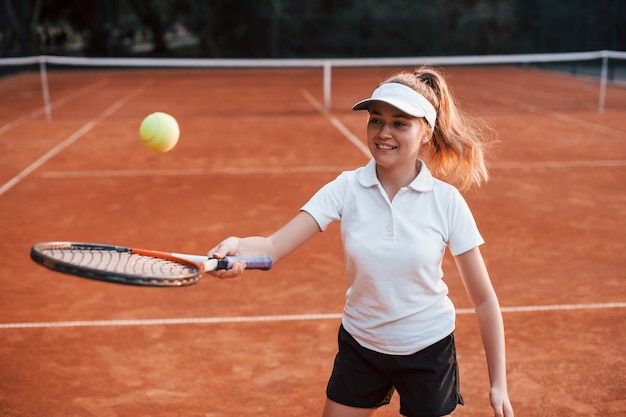 Giovane tennista in abiti sportivi è in campo all'aperto.