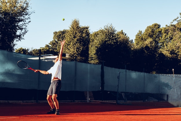 Giovane tennista professionista che fa un servizio
