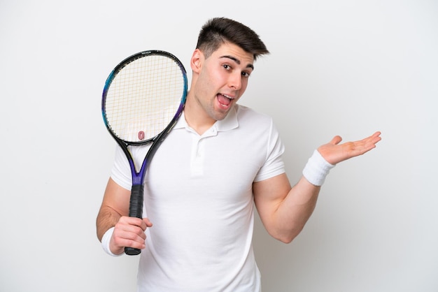 Giovane tennista uomo isolato su sfondo bianco con espressione facciale scioccata