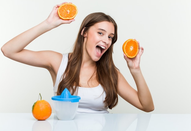 Giovane tenuta caucasica della donna che produce un succo d'arancia