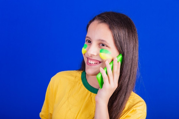 Giovane tifosa di calcio brasiliana che tiene la chiamata vocale del cellulare Applicazioni per smartphone