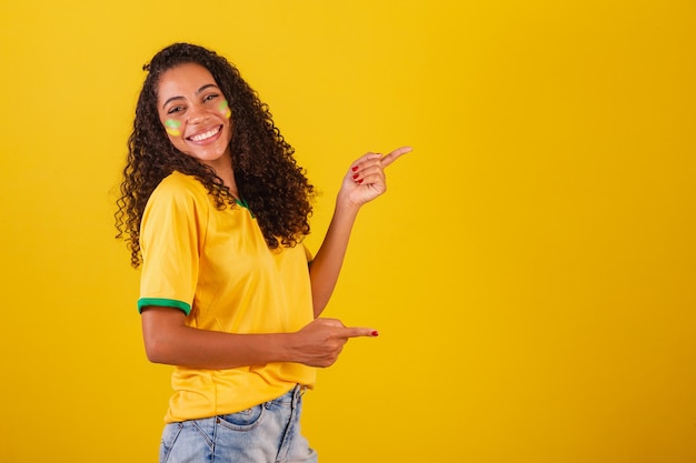 Giovane tifoso di calcio brasiliano nero che punta a destra la foto pubblicitaria