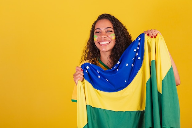 Giovane tifoso di calcio brasiliano nero donna con bandiera brasiliana tifo e festeggia