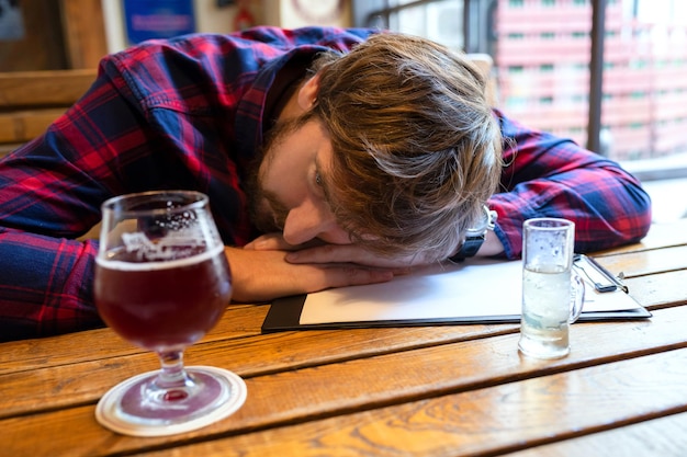 Giovane triste depresso che beve alcool da solo in un bar
