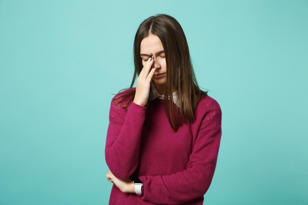 Giovane triste sconvolto perplesso disturbare bruna donna ragazza tenendo gli occhi chiusi, mettendo la mano sul naso in posa isolato su sfondo blu parete ritratto in studio. Concetto di stile di vita delle persone. Mock up spazio di copia.