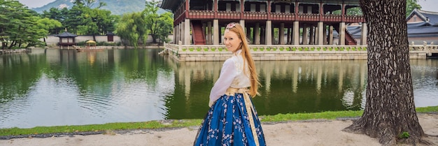 Giovane turista caucasica in abito nazionale coreano hanbok Concetto di viaggio in Corea Abbigliamento nazionale coreano Intrattenimento per turisti che provano abbigliamento nazionale coreano BANNER FORMATO LUNGO