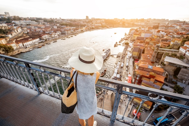 Giovane turista che gode di una splendida vista sulla città vecchia in piedi sul ponte di ferro durante il tramonto nella città di Porto, Portogallo