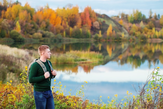 Giovane turista con lo zaino vicino al lago di autunno