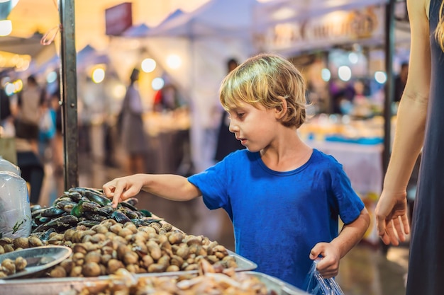 Giovane turista del ragazzo sul mercato alimentare asiatico di Walking Street