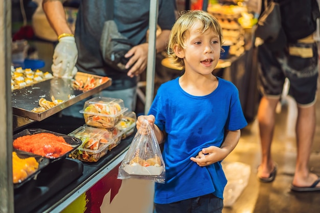 Giovane turista del ragazzo sul mercato alimentare asiatico di Walking Street