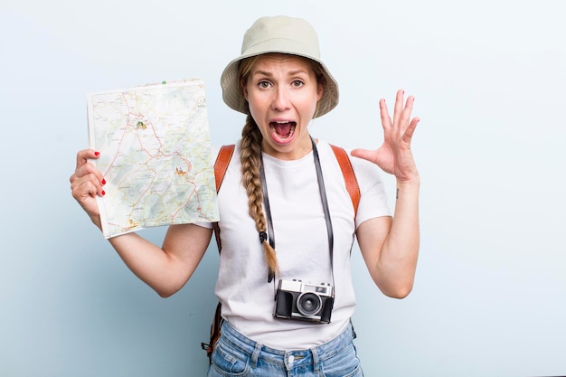 Giovane turista donna bionda adulta con un concetto di vacanze mappa