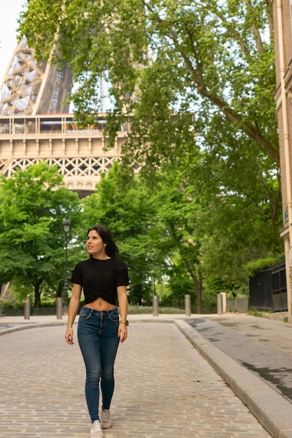 Giovane turista femminile che passeggia per una strada di Parigi felicemente con la Torre Eiffel sullo sfondo