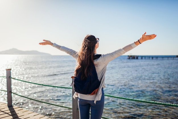 Giovane turista femminile con zaino che ammira il paesaggio del Mar Rosso e dell'isola di Tiran sul molo Concetto di viaggio Vacanze estive