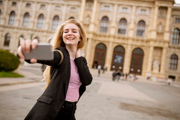 Giovane turista femminile prendendo selfie con foto mobile sulla strada nel centro di Vienna, Austria