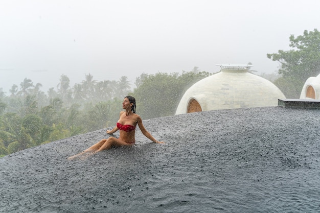 Giovane turista femminile serena con gli occhi chiusi che pratica la meditazione in una piscina all'aperto